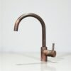 Rustic copper kitchen faucet with single-lever handle on farmhouse sink